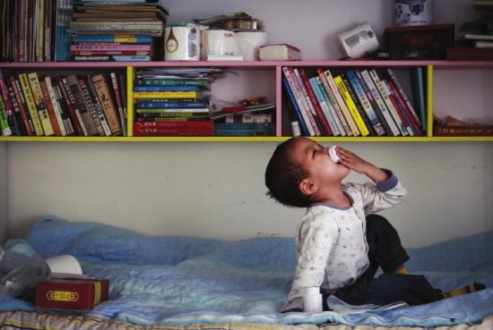 出租屋内，图图坐在床上自己吃药。 组图/潇湘晨报记者陈正