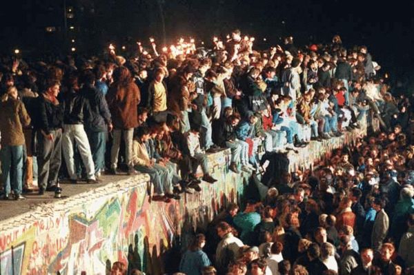 1989年11月9日，人群突破柏林墙，不少人爬上这堵见证意识形态对峙28年的墙体欢呼 图片来自德新社