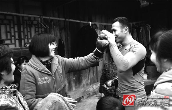 　　休息时，乡亲们与周志鹏练拳，体验搏击运动。